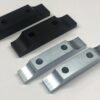 Four Motor Mounts - 8” with Standard 1/2" Plate - International Clamps, including two black and two silver ones, each featuring two holes, are arranged in two rows on a white surface.