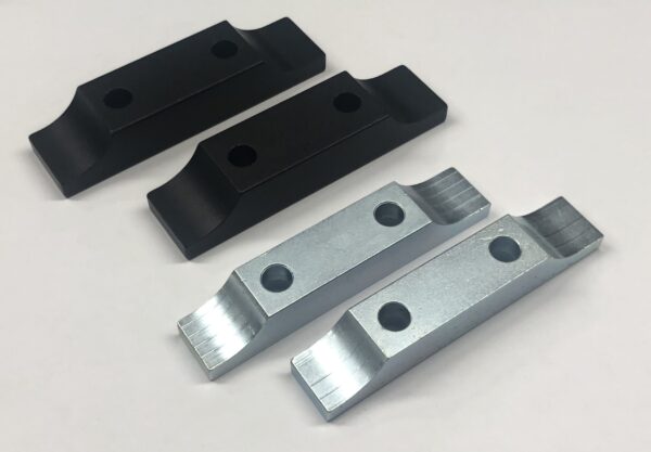 Four Motor Mounts - 8” with Standard 1/2" Plate - International Clamps, including two black and two silver ones, each featuring two holes, are arranged in two rows on a white surface.