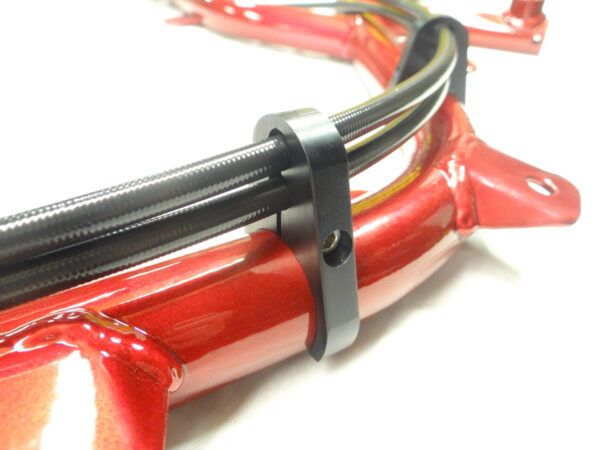 Close-up view of black cables secured with a Brake Line Rail Clamp - 1-1/4", attached to a glossy red metal frame.