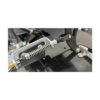 Close-up of a Junior Pedal Kit - Elevate Chassis 1" Rail, showcasing a mechanical component featuring a metal spring, bolts, and brackets, all attached to a black metal frame.