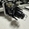 Close-up of the Foot Pan component for Elevate, Pursuit & Xpect CHAMP KART, featuring a black and white assembly with bolts and a fastening mechanism on a white background.