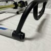 A close-up view of the Foot Pan for Elevate, Pursuit & Xpect CHAMP KART with a focus on the black handle and part of the white and yellow frame. The background is a plain white fabric.