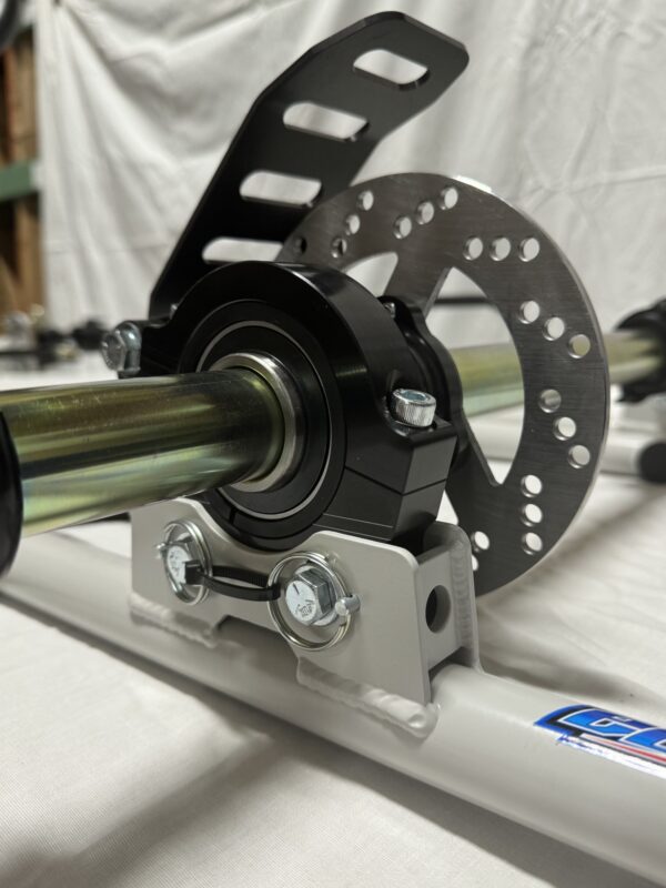 Close-up of a mechanical assembly featuring a Foot Pan from Elevate, Pursuit & Xpect CHAMP KART, showcasing a metal rod, a bearing with sleek black housing, and a perforated disc, all mounted on a pristine white framework.