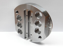 A machined metal component with eight circular holes and a central groove, standing against a white background.