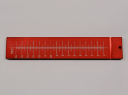 A red, rectangular ruler with centimeter markings from 1 to 16, featuring a small hole on one end.