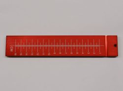 A red, rectangular ruler with centimeter markings from 1 to 16, featuring a small hole on one end.