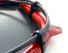 Close-up of a red circular metal structure with attached black cables held in place by black metal clamps.