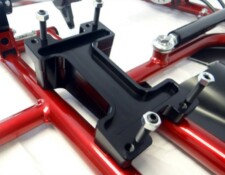 Close-up of a black metal bracket with several bolts attached to a red structural framework.