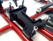 Close-up of a black metal bracket with several bolts attached to a red structural framework.