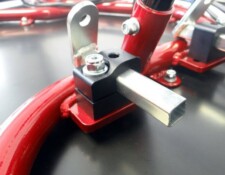 Close-up of a red metal frame with a square metal rod secured by a bracket and bolts.