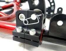 Close-up of a black and red metal bicycle part showing bolts, screws, and a tension pin.