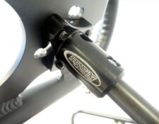 Close-up of a black metal mount with the text "PerforMance" attached to a circular structure, secured by multiple bolts.