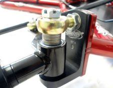 Close-up of a metallic pivot bolt assembly with a black and red frame, featuring a gold-colored bolt secured with a nut on top. The assembly is labeled with "10°-R" on the mounting plate.